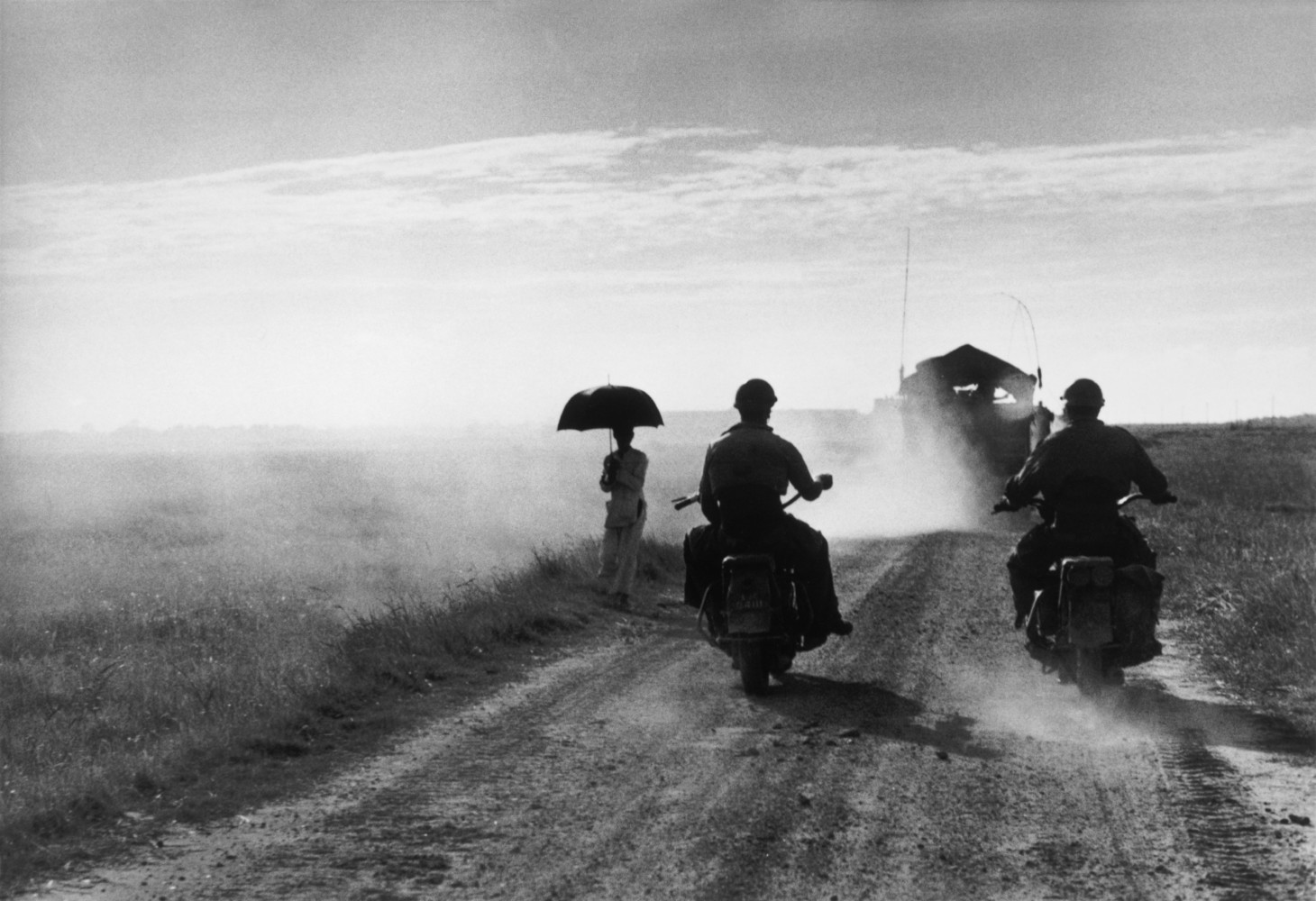 Robert Capa © International Center of Photography Motorcyclists and women walking on the road from Nam Dinh to Thai Binh. Indochina. May, 1954. © Robert Capa © International Center of Photography | Magnum Photos.
